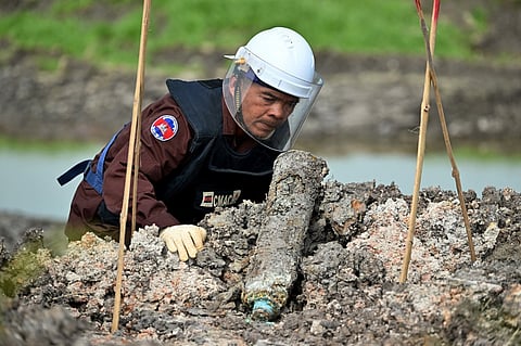 This photo taken on February 11, 2025 shows a deminer from the Cambodian Mine Action Centre (CMAC) examining an unexploded ordnance (UXO) that was unearthed by a worker during irrigation work in Svay Rieng province. Parts of Cambodia are still littered with unexploded ordnance from decades of conflict, and US President Donald Trump's decision to freeze virtually all American aid has seen many long-running projects to clear the deadly debris grind to a halt.