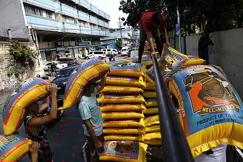 WORKERS load sacks of imported rice onto a truck along Dagupan Street in Tondo, Manila on Friday. The Department of Agriculture has reduced the maximum suggested retail price of imported rice to P49 a kilo starting tomorrow.