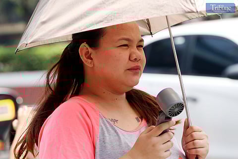 A WOMAN uses a portable fan while walking in Quezon City on Thursday, 6 March 2025, to relieve the intense heat.