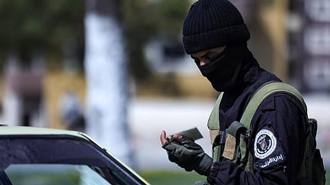 a picture released by the official Syrian Arab News Agency (SANA) shows a member of the Syrian forces checking the identity card of a driver at a checkpoint in Latakia, following deadly unrest