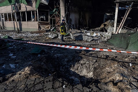 A Ukrainian rescuer stands next to a crater in front of a destroyed building following a drone attack in Odesa on March 8, 2025, amid the Russian invasion of Ukraine. Ukraine's President Volodymyr Zelensky said that the latest Russian air strikes that killed at least 12 people demonstrated that Russia's objectives remained "unchanged" and new sanctions were needed.