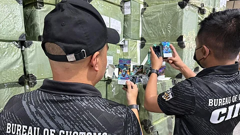 Members of the Bureau of Customs inspect the seized illegal vapes and used clothing at a warehouse in Valenzuela City last Thursday.