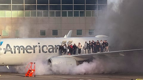 This image courtesy of Branden Williams shows passengers standing on the wing of an American Airlines plane as they are evacuated after it caught fire while at a gate at Denver International Airport in Denver, Colorado, 13 March 2025.