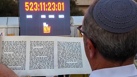 A man at 'Hostages Square' in Tel Aviv reads in front of a clock counting the time Israeli hostages have been held captive in Gaza, during the reading of the Scrolls of Esther at the start of the Jewish holiday of Purim