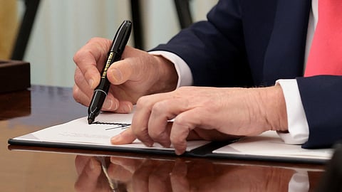 WASHINGTON, DC – U.S. President Donald Trump signs executive orders in the Oval Office of the White House.