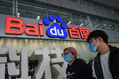 (FILES) People walk past a Baidu logo outside the company headquarters in Beijing on February 2, 2024. Chinese internet search giant Baidu released a new artificial intelligence reasoning model on 16 March 2025 and made its AI chatbot services free as ferocious competition grips the sector.