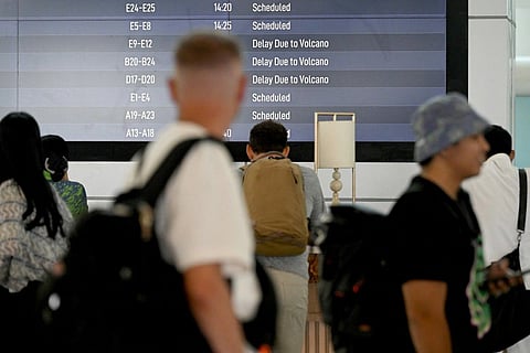 Passengers look at an electronic board displaying cancelled flights at the Ngurah Rai International Airport in Tuban near Denpasar on Indonesia's resort island of Bali on March 21, 2025, after Mount Lewotobi Laki-Laki volcano erupted.