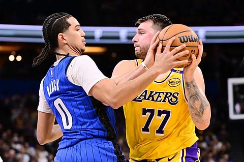 Luka Doncic, right, of the Los Angeles Lakers looks to pass the ball against Anthony Black #0 of the Orlando Magic in the first half of a game at Kia Center on March 24, 2025 in Orlando, Florida, US