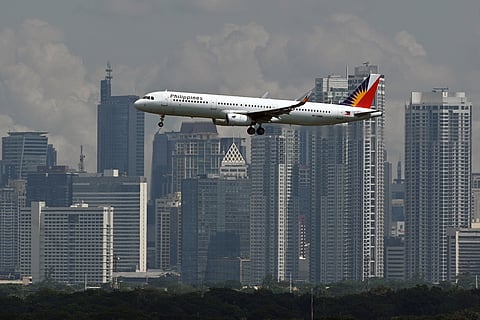 Philippine Airlines Airbus A321 passenger aircraft prepares to land at the Ninoy Aquino International Airport as the skyline of the Makati business center is seen from Taguig City.