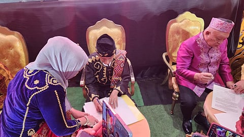35th Sultan Phugdalun Kiram II signs the Covenant of Three Mindanao Sultanates, assisted by Dayang Dayang Shvethlana Kiram, Royal Daughter of the 34th Sultan Esmail Kiram II.