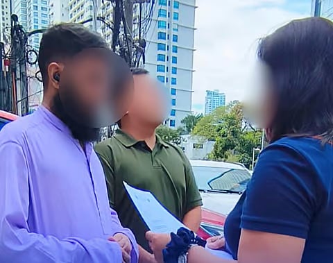 Operatives from the Bureau of Immigration speak with the Pakistani they arrested for overstaying in the country.