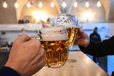 Two men clink their beer mugs filled with 'Pilsner Urquell' beer in the 'U Rarasku' pub in Prague, Czech Republic, on March 19, 2025. The Czech beer-making tradition is over a thousand years old, and beer is omnipresent in Czech history and culture.