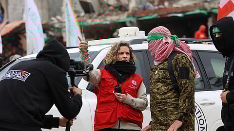 A member of the International Red Cross speaks to Hamas fighters at the site of the handing over of two Israeli hostages in Rafah in the southern Gaza Strip on February 22, 2025.