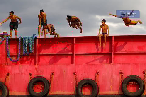 Residents of Baseco beat the heat by jumping off a barge moored at the seawall in Tondo, Manila.