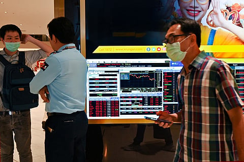 A man wearing a protective face mask walks past an electronic quotation board displaying share prices of Bangkok Stock Exchange in Bangkok on 29 February 2020. Global stocks slumped again on February 28 to mark the largest weekly drop since the 2008 global financial crisis over fears the coronavirus could wreak havoc on the world economy.
