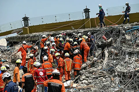 Myanmar and Chinese rescuers carry the body of a victim that was trapped under the rubble of the collapsed building 'Sky Villa Condominium development' in Mandalay on April 2, 2025, five days after a major earthquake struck central Myanmar. Days after a shallow 7.7-magnitude earthquake that killed more than 2,000 people, many people in Myanmar are still sleeping outdoors, either unable to return to ruined homes or afraid of further aftershocks.