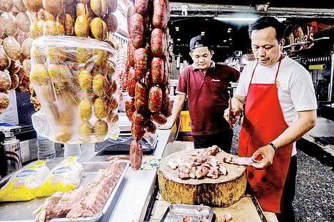 A meat vendor chops pork purchased by a customer inside a market in Quezon City on Wednesday.