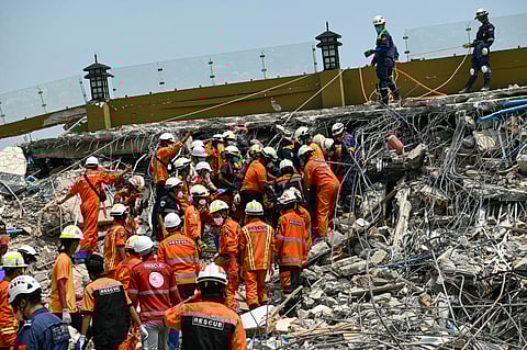 Myanmar and Chinese rescuers carry the body of a victim that was trapped under the rubble of the collapsed building 'Sky Villa Condominium development' in Mandalay on April 2, 2025, five days after a major earthquake struck central Myanmar. Days after a shallow 7.7-magnitude earthquake that killed more than 2,000 people, many people in Myanmar are still sleeping outdoors, either unable to return to ruined homes or afraid of further aftershocks.