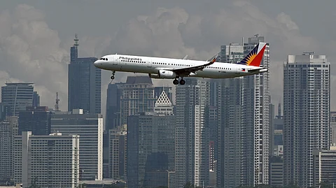 Philippine Airlines Airbus A321 passenger aircraft prepares to land at the Ninoy Aquino International Airport as the skyline of the Makati business center is seen from Taguig City.