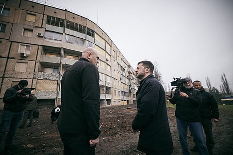 This handout photograph taken and released by the Ukrainian Presidential Press Service on April 11, 2025, shows Ukraine's President Volodymyr Zelensky (R) and Head of the Dnipropetrovsk Regional Military Administration Serhiy Lysak (L) standing in front of a damaged residential building as they visit the site of the strike to honour the memory of those killed in a Russian missile strike on Kryvyi Rig, amid the Russian invasion of Ukraine.