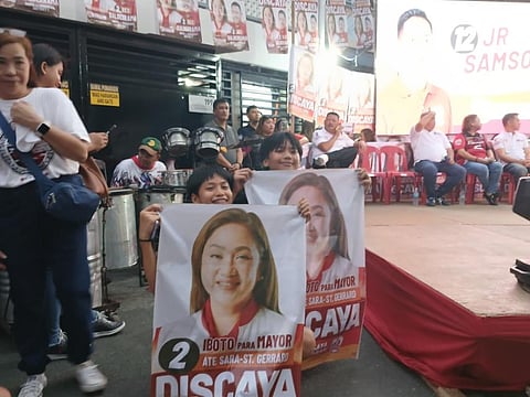 TWO boys hold tarpaulins of Pasig mayoral candidate Ate Sarah Discaya during a public caucus in Barangay Sumilang on Monday evening. Discaya has pledged to provide a P500 monthly allowance to all students enrolled in public elementary and high schools if elected.