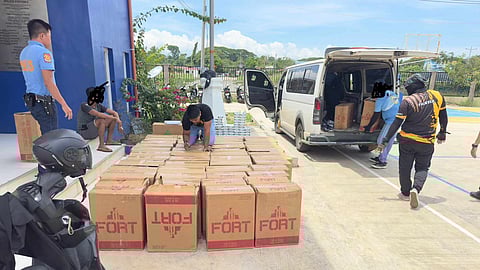 Authorities unload boxes of smuggled cigarettes from a white van intercepted at a checkpoint in Barangay Sicsican, Puerto Princesa City on 15 April. The seized contraband, worth P944,000, is now in police custody.