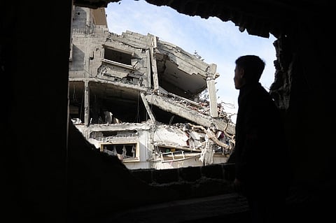 A Palestinian youth looks through a damaged building's window onto the destruction following overnight Israeli strikes on a residential area in Jabalia's southwestern district of Nazla in the northern Gaza Strip, on April 16, 2025. Israel resumed its intense military offensive in the Palestinian territory after a ceasefire deal that came into effect on January 19 fell apart two months later over differences regarding its next phase. Hundreds of thousands of people have since been displaced.