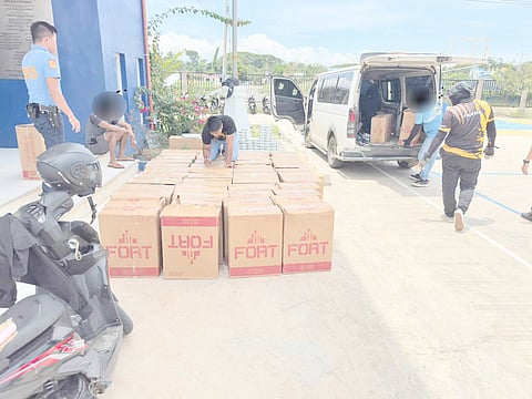 AUTHORITIES examine the 54 boxes and one sack of smuggled cigarettes worth P944,000 loaded in a van after it was intercepted at a checkpoint in Barangay Sicsican, Puerto Princesa City on Tuesday.