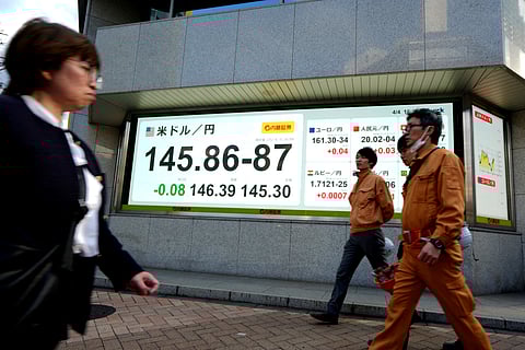 Pedestrians walk past an electronic board showing the foreign exchange trading price of the Japanese yen against the US dollar on a street in Tokyo on 4 April 2025