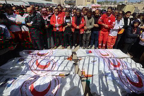 Members of the Palestine Red Crescent and other emergency services pray by the bodies of fellow rescuers killed a week earlier by Israeli forces, during a funeral procession at Nasser hospital in Khan Yunis in the southern Gaza Strip on March 31, 2025. Bodies of eight medics from the Red Crescent, six members of Gaza's civil defence agency and one employee of a UN agency were retrieved, the Red Crescent said in a statement on March 30.