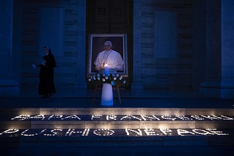 A Catholic nun walks past a portrait of the late Pope Francis displayed at the St. Mother Teresa Cathedral in Pristina on 21 April 2025. Pope Francis, an energetic reformer who inspired widespread devotion from Catholics but riled traditionalists, died on 21 April 2025 aged 88.
