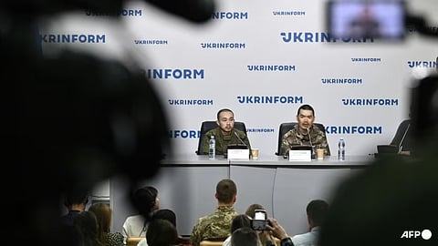 Chinese prisoners of war under armed guard Zhang Renbo (left) and Wang Guangjun (right) attend a press conference in Kyiv on Apr 14, 2025, amid the Russian invasion of Ukraine.