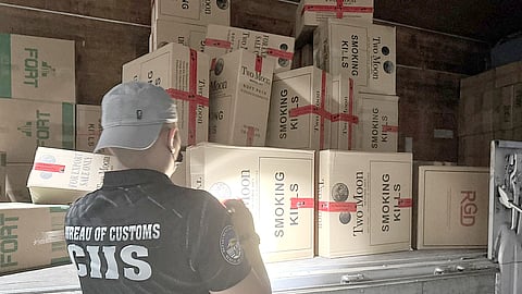 A personnel of the Bureau of Customs-Customs Intelligence and Investigation Service inspects smuggled cigarettes worth P83.7 million seized from a warehouse in Bocaue, Bulacan on Thursday.