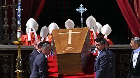 Pallbearers carry the wooden coffin of Pope Francis during the funeral rites at St. Peter's Basilica, with cardinals in the background.
