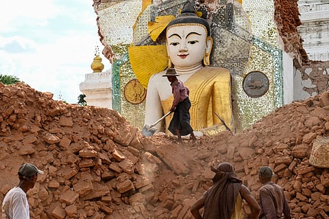 This photo taken on April 12, 2025 shows people clearing the debris around a damaged Buddha statue at Lawkatharaphu Pagoda in Inwa on the outskirts of Mandalay, following the devastating March 28 earthquake. When a massive earthquake hit Myanmar last month, centuries of sacred history tumbled down -- towering Buddha idols, sky-scraping stupas and the pure-white pagoda where 83-year-old Khin Sein has prayed for most of her life.