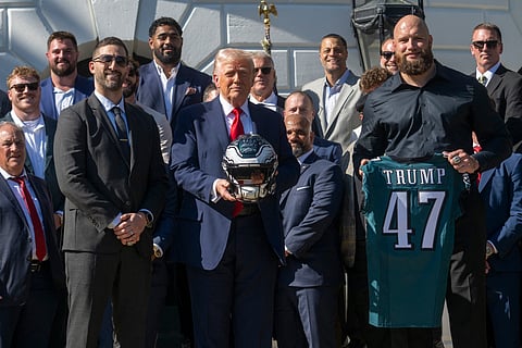 US President Donald Trump holds up a helmet, flanked by Philadelphia Eagles' tackle #65 Lane Johnson (R) and Philadelphia Eagles head coach Nick Sirianni (L), as he hosts an event celebrating the Philadelphia Eagles, 2025 Super Bowl champions, at the White House on April 28, 2025, in Washington, DC. The Eagles defeated the defending champion Kansas City Chiefs 40-22 in Super Bowl LIX, held in New Orleans, Louisiana on February 9, 2025.