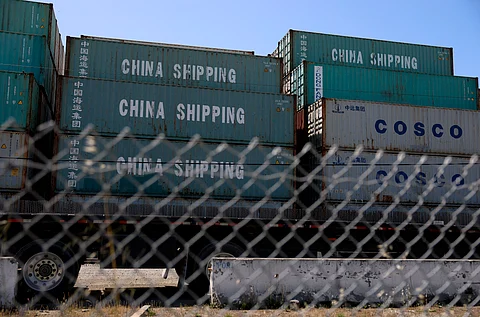 Shipping containers labeled "China Shipping" and "COSCO" are stacked behind a chain-link fence at the Port of Oakland, California, on 28 April 2025, amid a surge in canceled sailings from China due to ongoing U.S. tariffs.