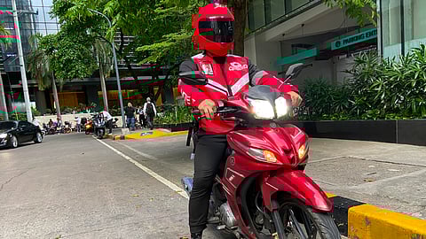 A MOVE IT driver gets ready for a service drive in Makati City. MOVE IT is currently grappling with an order by the Land Transportation Franchising and Regulatory Board for the motorcycle taxi company to reduce its operational fleet. MOVE IT management said it will appeal the order.
