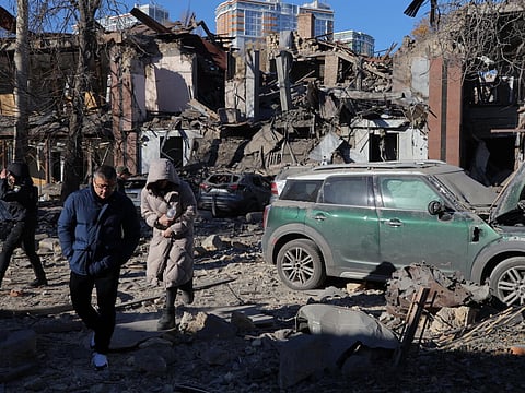 Local residents and police walk next to damaged cars and a destroyed building following a missile attack in Odesa, Ukraine.