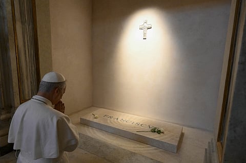 Pope Leo XIV prays before the tomb of late Pope Francis at Santa Maria Maggiore Basilica in Rome, in a photo released by The Vatican Media on 10 May 2025. A white rose rests on the marble slab engraved with "Franciscus" beneath a cross on the wall.