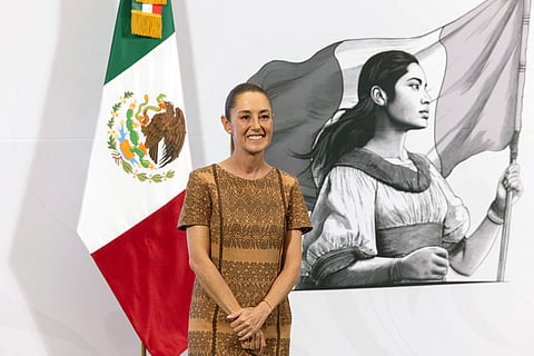 Mexican President Claudia Sheinbaum smiles during her daily press conference at the National Palace in Mexico City on 9 May 2025, with the Mexican flag and a patriotic mural in the background. Sheinbaum announced that Mexico has filed a lawsuit against Google for renaming the Gulf of Mexico to "Gulf of America" for U.S. users.