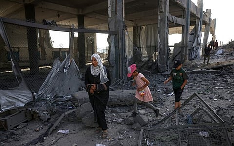 Displaced Palestinians walk amid the rubble of an UNRWA aid supply depot and shelter, heavily damaged in an overnight Israeli strike in Jabalia, in the northern Gaza Strip on May 10, 2025.