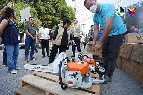 DENR Secretary Maria Antonia Yulo-Loyzaga (center) inspects seized chainsaws at a warehouse in Valenzuela City.