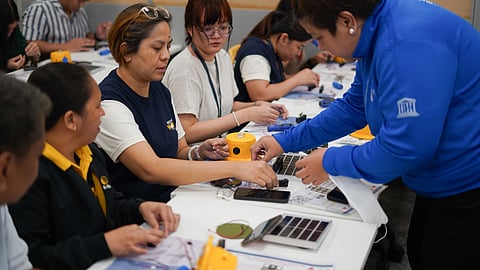 Sun Life Philippines volunteers get pointers on assembling a solar lamp during a Circle of Light workshop.