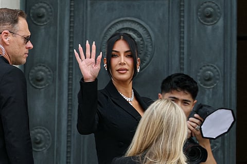 US celebrity Kim Kardashian (C) waves as she arrives at the Assize Court for the trial during which she will testify over the 2016 robbery that saw her relieved of millions of dollars' worth of jewellery at gunpoint in Paris, on May 13, 2025. The trial of this sensational nine million euro jewellery robbery opened in Paris on April 28, 2025.