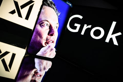 A photo taken on 13 January 2025 in Toulouse shows screens displaying the logo of Grok, the AI chatbot developed by xAI, alongside an image of xAI founder Elon Musk, whose face appears on a smartphone screen reflected on a glossy surface.