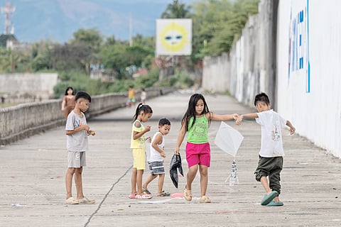 CHILDREN make the most of a warm afternoon, flying kites and playing along a concrete path. As temperatures rise, their laughter fills the air, a reminder of simple joys despite the heat.