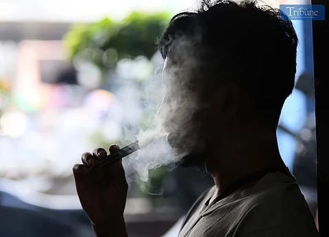 A silhouetted person exhales a large cloud of vapor while using an e-cigarette, highlighting the growing issue of youth vaping in the Philippines.