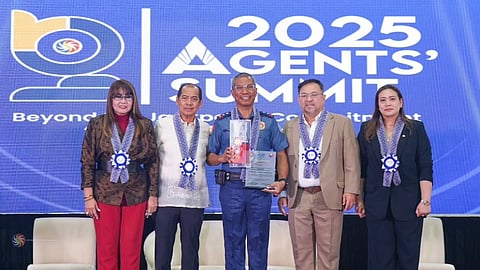 Police Major General Nicolas D. Torre III receives a plaque of appreciation onstage alongside four PCSO officials at the 2025 Agentsโ Summit, with a large event backdrop displaying the summit theme behind them.