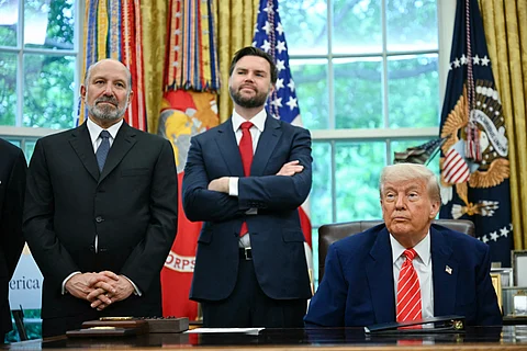 US President Donald Trump sits at the Resolute Desk in the Oval Office as US Secretary of Commerce Howard Lutnick (left) and US Vice President JD Vance (center) stand behind him during a trade announcement at the White House in Washington, DC.